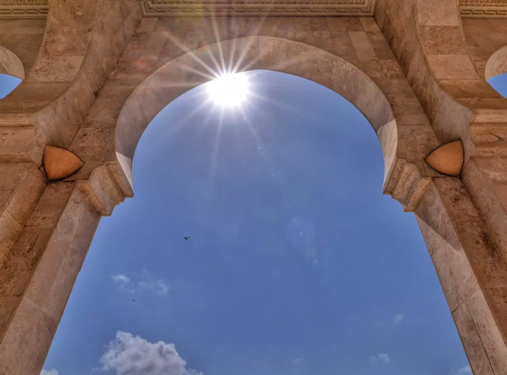 The sun framed by an arch at a mosque in Casablanca, Morocco.