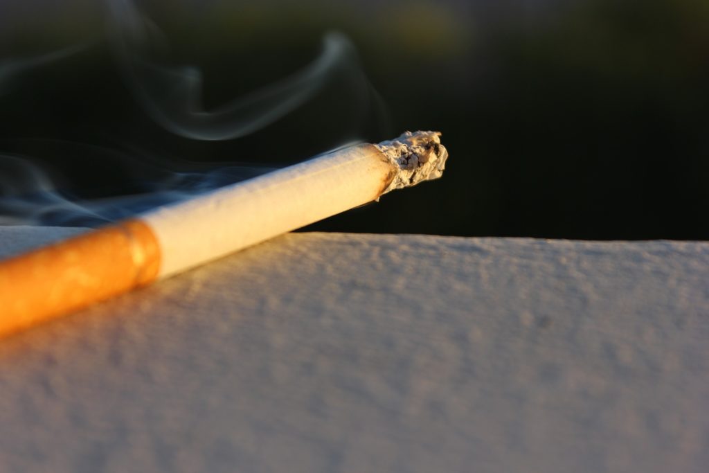 A lit cigarette burning on a ledge.