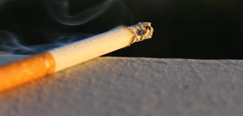 A lit cigarette burning on a ledge.