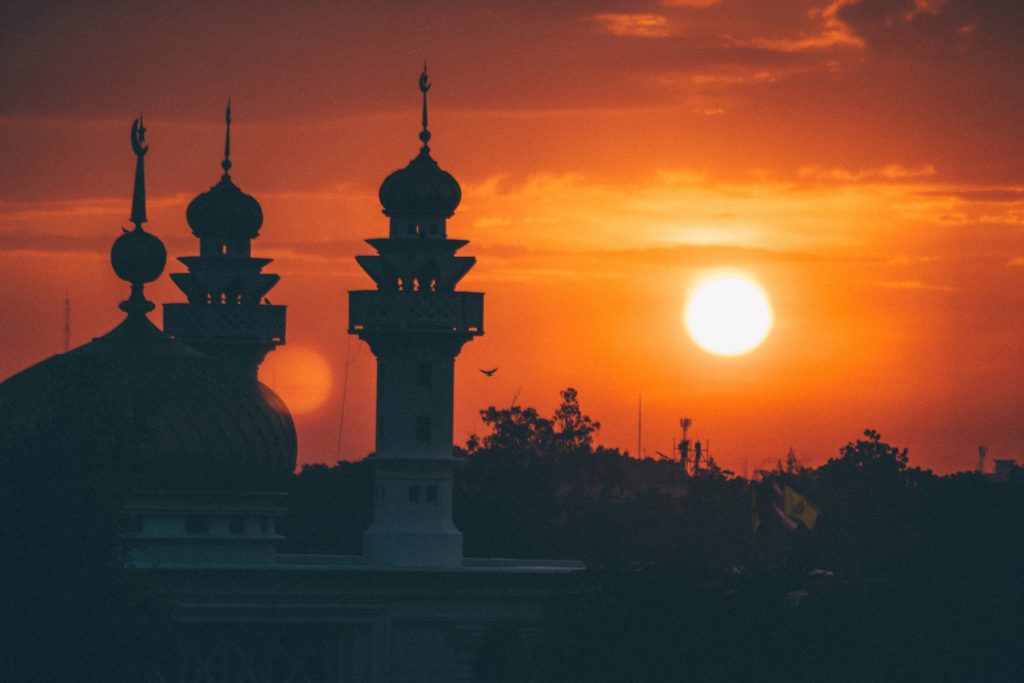 A mosque silhouetted against the sky at sunrise.