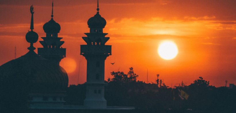 A mosque silhouetted against the sky at sunrise.