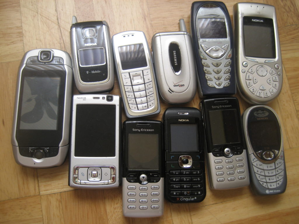 Old-model cellular phones lined up on a table.