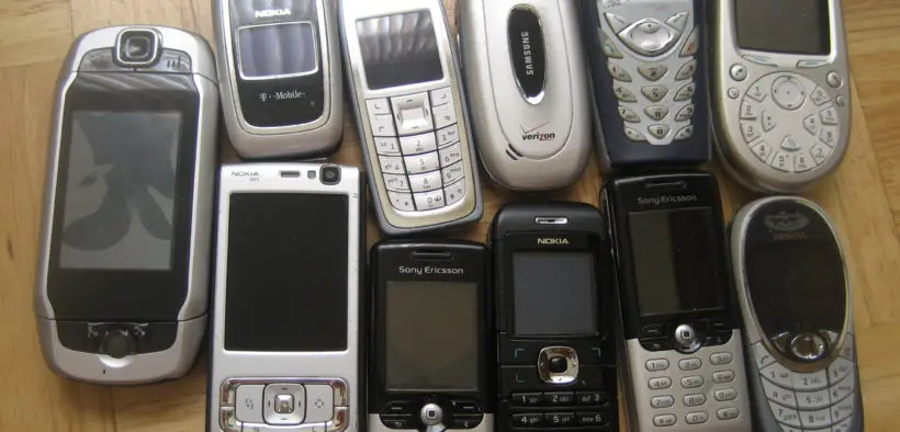 Old-model cellular phones lined up on a table.