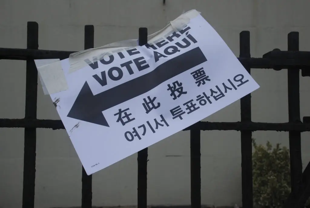 Sign reading "Vote Here" in several different languages.