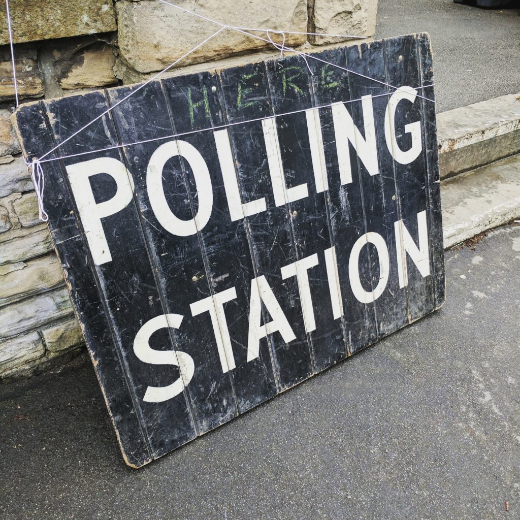 Old, weathered sign saying "POLLING STATION."
