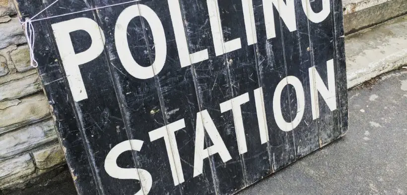 Old, weathered sign saying "POLLING STATION."
