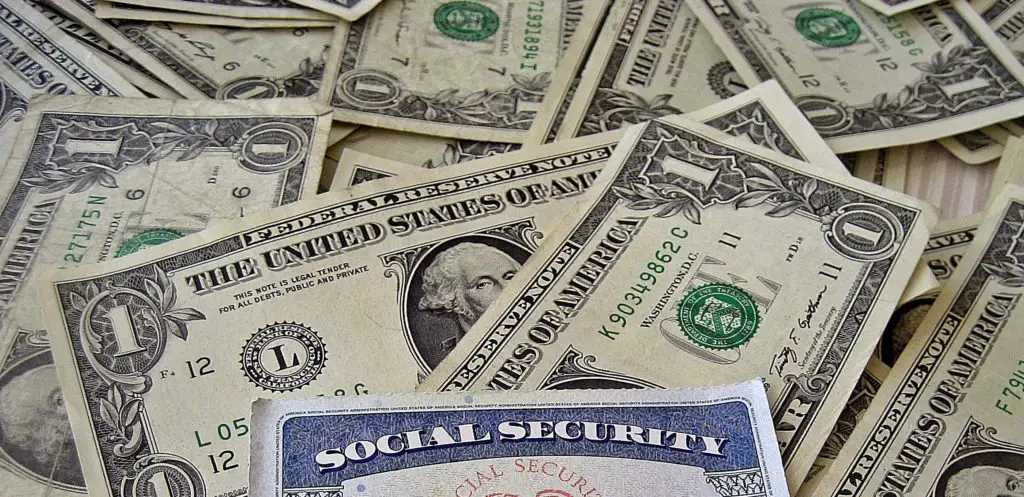 Social Security card atop a pile of United States dollars.