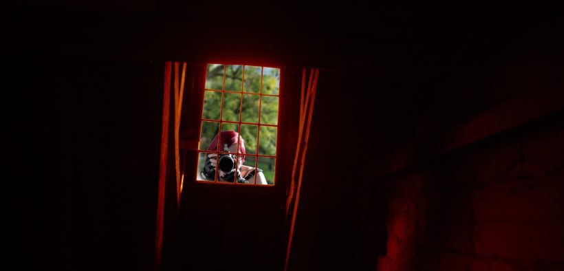 Woman at a window taking photos of the inside of a home.